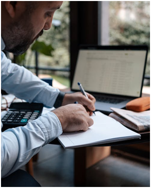 A man working on a notepad with a laptop on the table