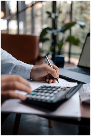 A person using a calculator while writing on paper