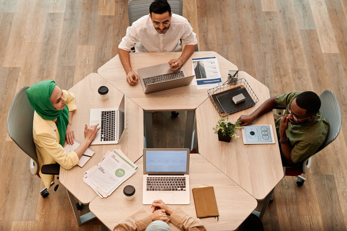 Four employees conducting an assurance service using laptops 