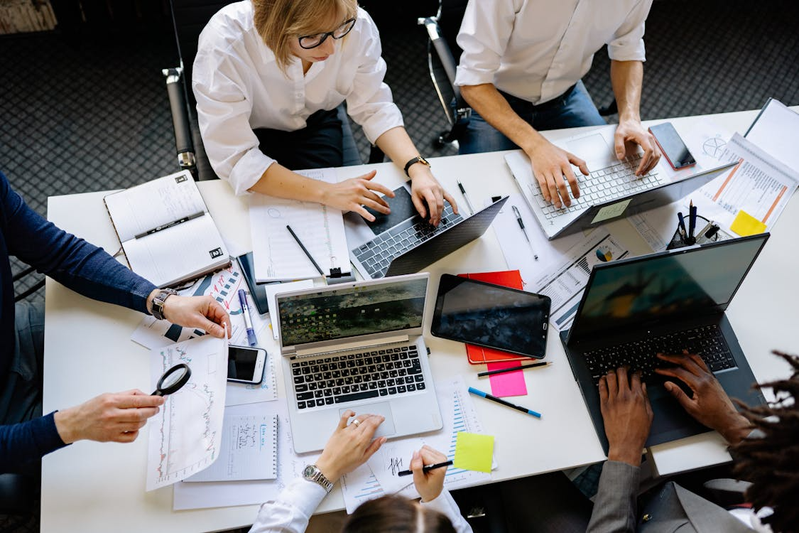 A group of employees conducting an audit with laptops and sheets on the table