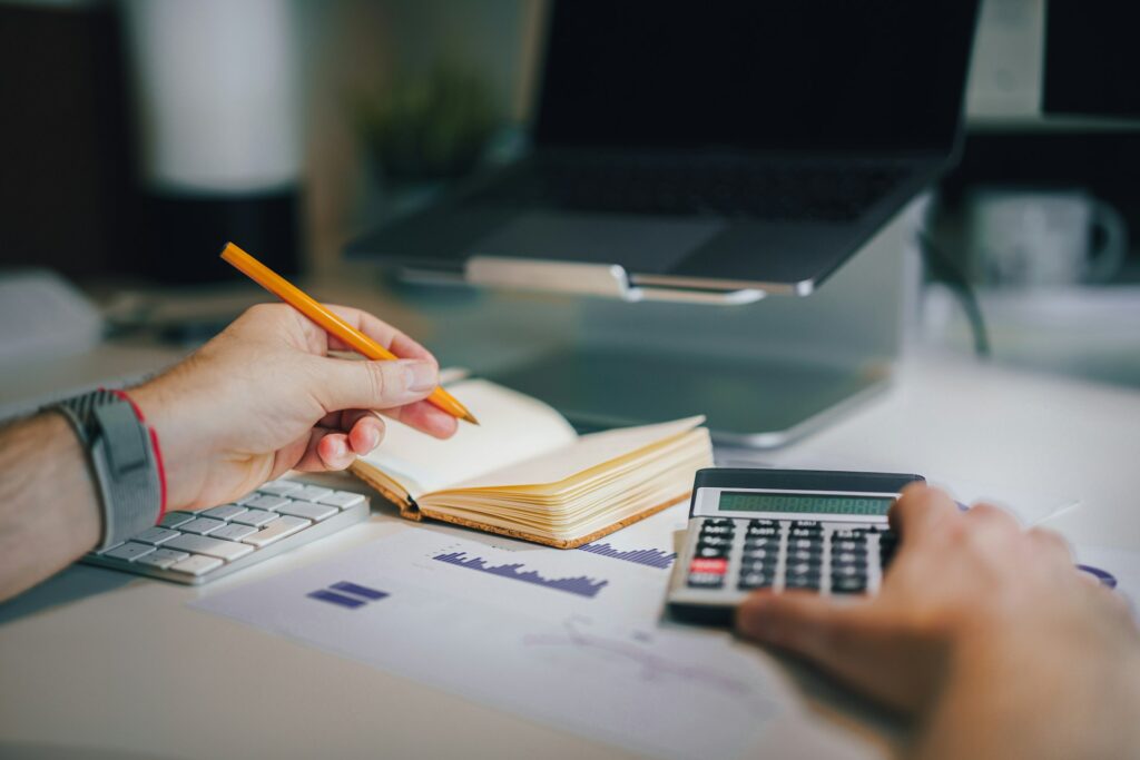 A person sitting at a desk with a calculator and notebook 