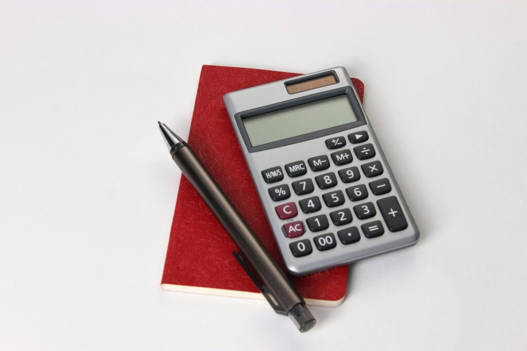 A calculator and pen on top of a notebook