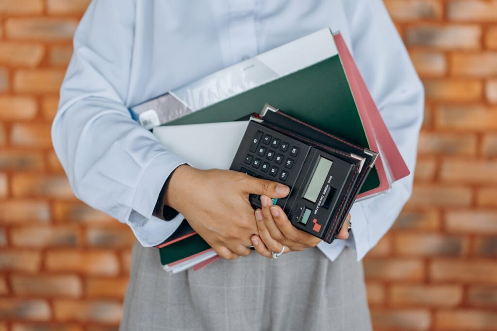 a person holding a calculator and folders